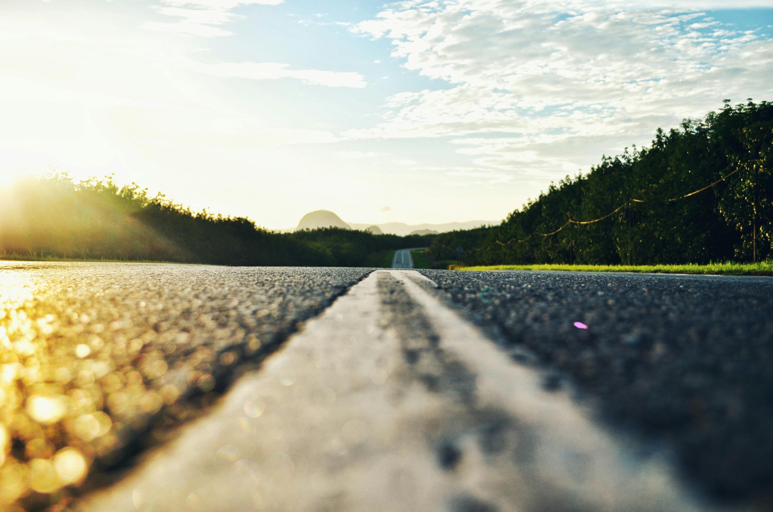Serene road stretching through lush landscape during sunset in Kangar, Malaysia.